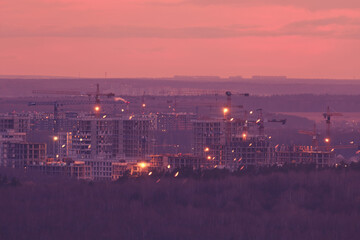 Sunset sky over under construction city buildings with tower cranes