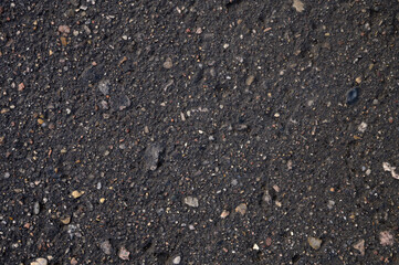 Abstract background of black wet asphalt with inclusions of pebbles