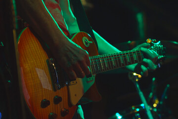 The guitarist plays his guitar in the spotlight