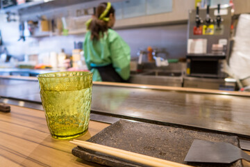 Yellow glass of fresh water with ice and empty plate on dining table. They are in a japanese restaurant.