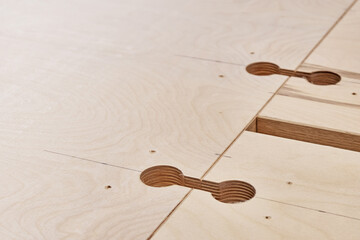 Part of new large wooden dining table with insert holes for worktop connectors in light workshop of...