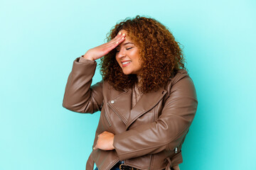 Young latin curvy woman isolated on blue background blink at the camera through fingers, embarrassed covering face.