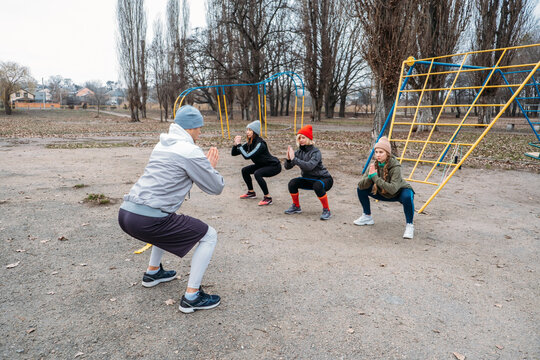 Group Fitness Workout Classes Outdoors. Socially Distant Outdoor Workout Classes In Public Parks. Three Women And Man Training Together In The Public Park. Health, Wellness And Community Concept