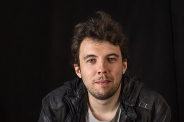 Portrait of a young dark-haired man with bokeh effect on a dark background