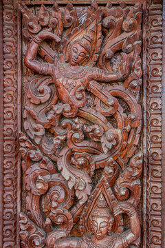 Art of ancient wood carving of deity on wooden door. Thai traditional Buddhist design at Wat Nong Waeng temple in Khon Kaen province, Thailand.