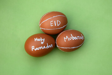 Obraz na płótnie Canvas Holy Ramadan and Eid Mubarak hand typography on the egg. Green isolated background.