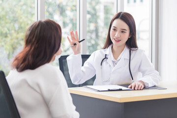 Obraz premium Asian professional doctor woman who wears medical coat talks with woman patient to suggest treatment guideline and healthcare concept in office of hospital.