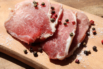 Raw pork chops on cutting board. Uncooked meat steaks for grilling with spices, pepper, salt and...