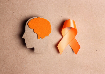  Orange awareness ribbon and brain symbol on a brown background.