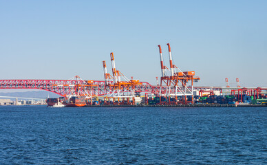 OSAKA, JAPAN - MAR 10, 2019: Cranes and cargo container ship near Minato Bridge. They are at sea port in Osaka bay, Japan.