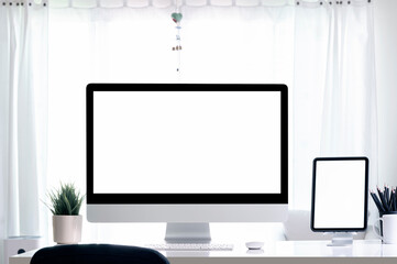 Creative workspace with blank white screen computer monitor and tablet on white wooden table.