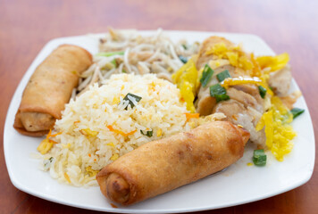 Fried rice with spring rolls, meat pieces, spicy peppers and soy bean sprouts. Traditional Chinese food plate