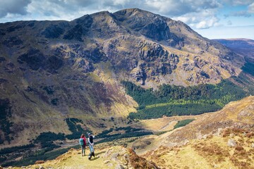 Obraz premium Couple and their dog on Haystacks looking towards Pillar. English Lake District.