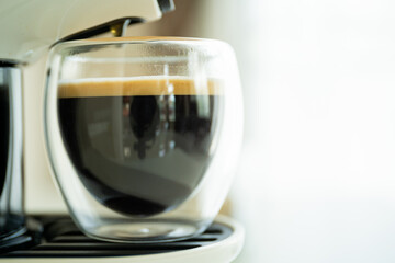 Espresso coffee in a cup brewed by capsule espresso coffee machine.