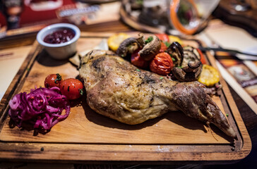 a piece of fried lamb with vegetables and a side dish on a wooden board 