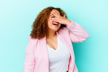 Young latin curvy woman isolated on blue background covers eyes with hands, smiles broadly waiting for a surprise.