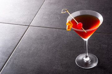 Traditional Manhattan cocktail with cherry on black stone. Copy space