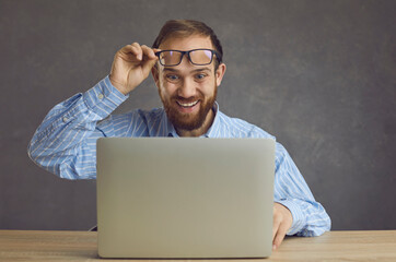 Funny excited surprised man takes off glasses looking at screen of laptop computer device. Happy...