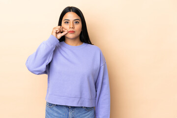 Young latin woman woman over isolated background showing a sign of silence gesture