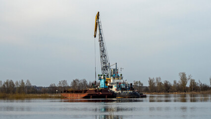 Fototapeta na wymiar Dredger is working to deepen the fairway on the river. Cleaning and deepening by a dredger on the river. Sunset on the river. Industrial concept.