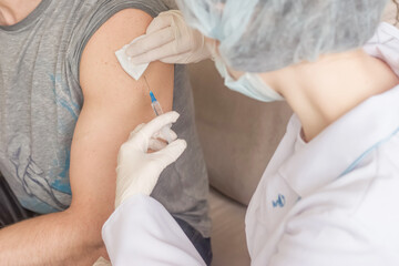 A nurse makes a vaccination to a man indoors
