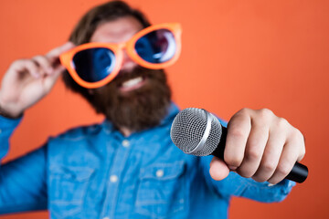 modern technology. male sing music in microphone. funny bearded man with mic. brutal hipster in party glasses. karaoke singer. unshaven guy with groomed long hair