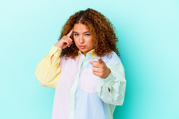 Young latin curvy woman isolated on blue background pointing temple with finger, thinking, focused...