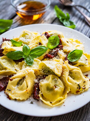 Tortelloni stuffed with ricotta cheese, basil pesto and vegetables on wooden table
