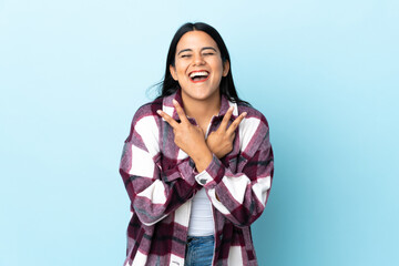 Young latin woman woman isolated on blue background smiling and showing victory sign