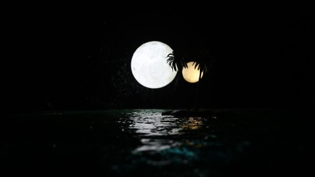 Romantic night scene. Fantasy night landscape with little island with palms and full moon over sea. Creative table decoration. Silhouette of romantic couple on uninhabited island. Selective focus.