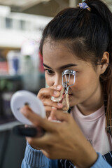 Close-up face beautiful young woman using eyelash curling device.