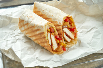 Appetizing doner roll with vegetables, sauce and tofu in pita bread, served on paper on a light...