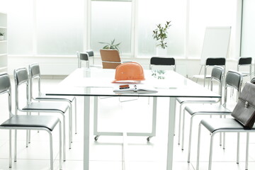 Flipchart construction helmet chairs briefcase phone handle glass table in a bright office space