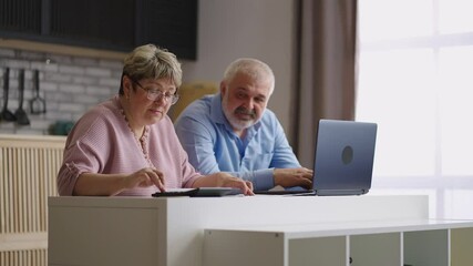 pair of retirees are counting their expenses and income sitting together at kitchen in apartment, old man and woman