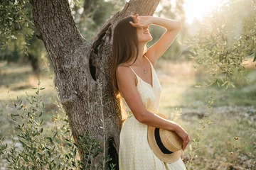  portrait of beautiful young brunette woman in straw hat at sunset in olive garden. Travel to Italy, summer vacation © Oleksandr