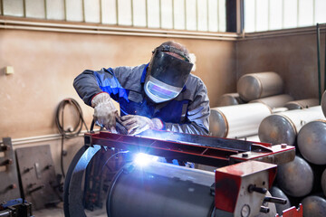Worker is welding metal tubes, man hand welding inox boiler with argon gas