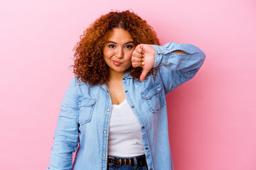 Young latin curvy woman isolated on pink background showing thumb down, disappointment concept.