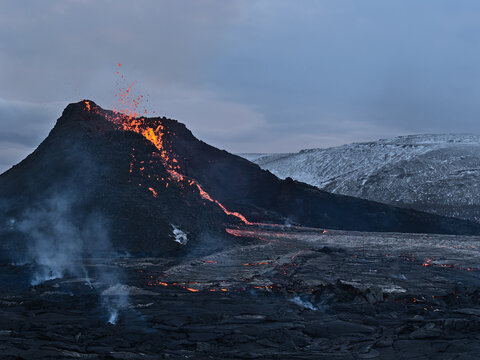 Stunning view of recently erupted volcano in Geldingadalir valley near Fagradalsfjall mountain, Grindav&iacute;k, Reykjanes peninsula, southwest Iceland with hot lava flows and smoke in the evening.