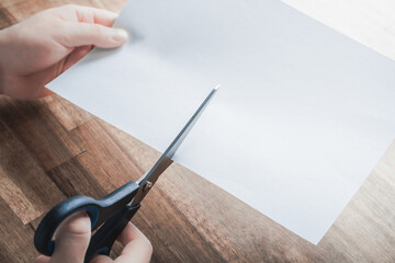 Pair Of Scissors Cutting White Paper, Holded By Male Hands