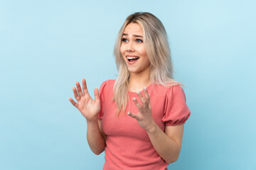 Fototapeta premium Teenager girl over isolated blue background with surprise facial expression