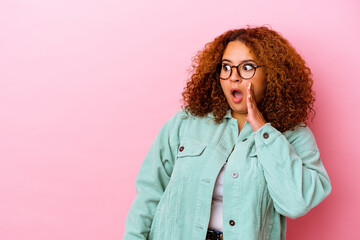 Young latin curvy woman isolated on pink background being shocked because of something she has seen.