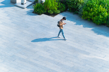 Aerial top view of man with face mask walks on across pedestrian street with black silhouette...