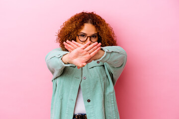 Young latin curvy woman isolated on pink background standing with outstretched hand showing stop sign, preventing you.