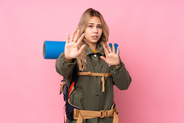 Teenager Russian mountaineer girl with a big backpack isolated on pink background nervous stretching hands to the front