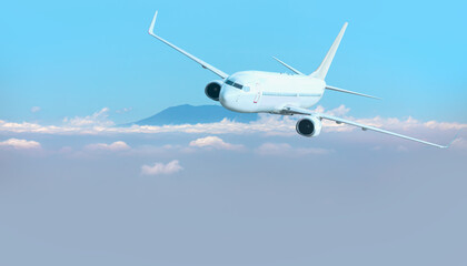 A passenger airplane flying over the clouds and a mountain peak in the background