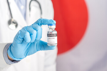 A doctor in blue gloves holding a bottle with the vaccine while standing with the Canada flag background. Close-up shot. Medicine and healthcare concept.