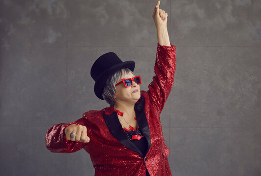 Portrait Of Happy Funny Senior Woman In Retro Style Outfit Feeling Free And Having Fun On Gray Background. Crazy Drunk Grandma And Mother-in-law Acting As Dancing Party Queen And DJ At Family Holiday