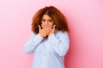 Young latin curvy woman isolated on pink background covering mouth with hands looking worried.