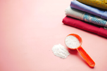 Washing powder in plastic spoon on blue background 