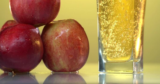 close-up of pouring juice into a glass. there are fresh red apples on the table nearby. 4k video